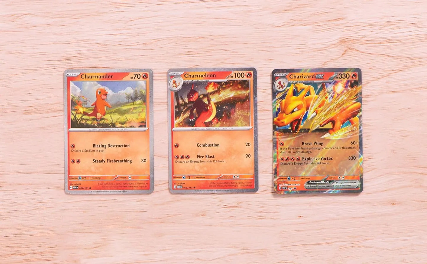 Promos Charizard ex, Charmeleon y Charmander sobre mesa de madera